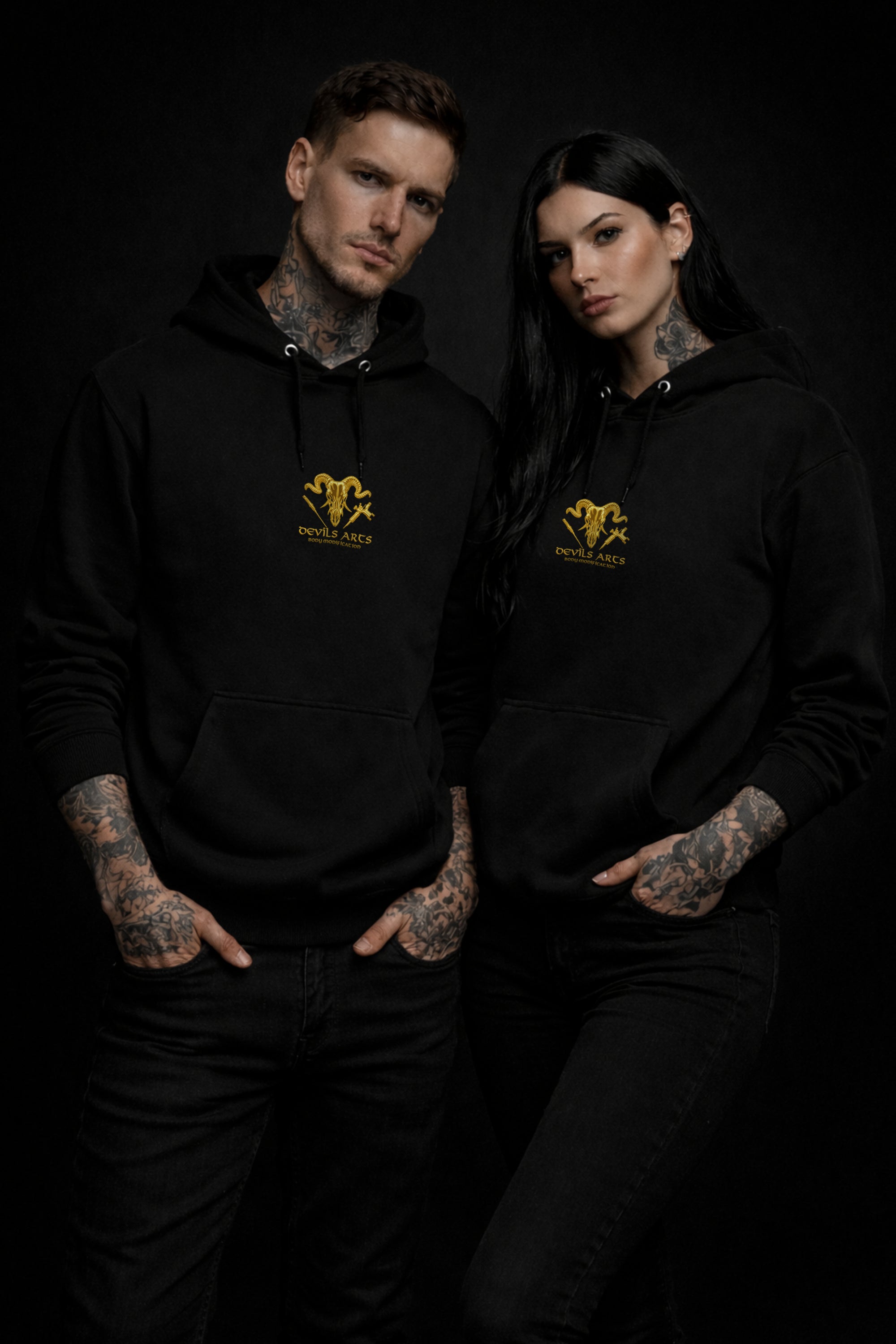 tattooed male and female models wearing black DEVILS ARTS gold skull logo hoodie dark tattoo streetwear