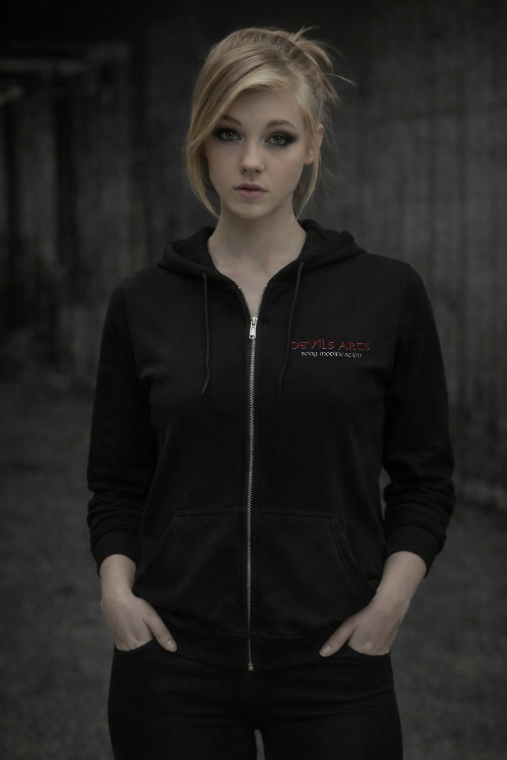 female model wearing black DEVILS-ARTS zip hoodie with small chest logo dark tattoo streetwear