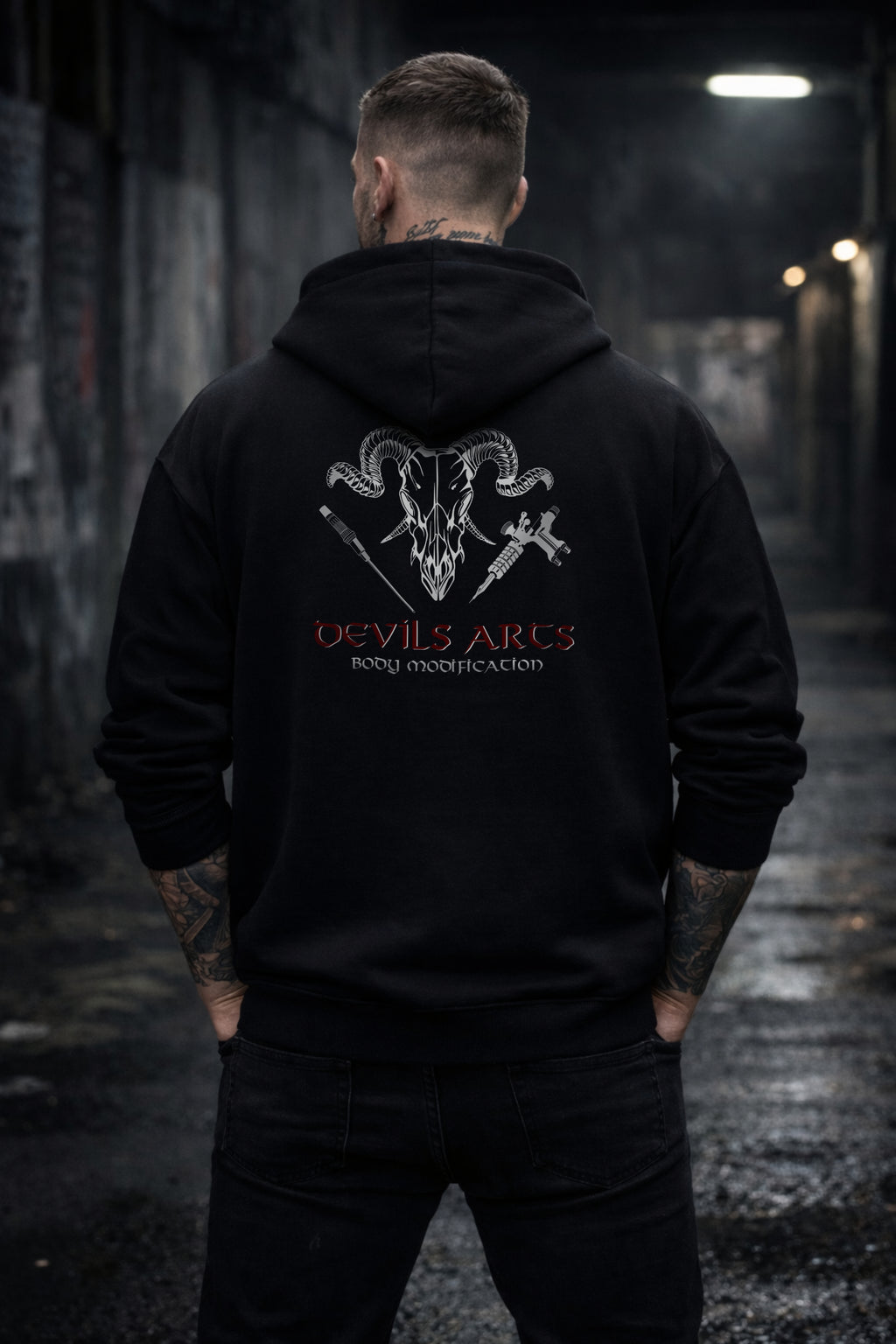 tattooed male model wearing black DEVILS-ARTS hoodie with large skull logo back print tattoo streetwear